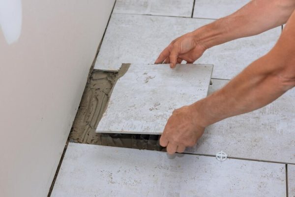 tiler-placing-ceramic-floor-tile-position-adhesive-with-process-bathroom-reconstruction_73110-17296